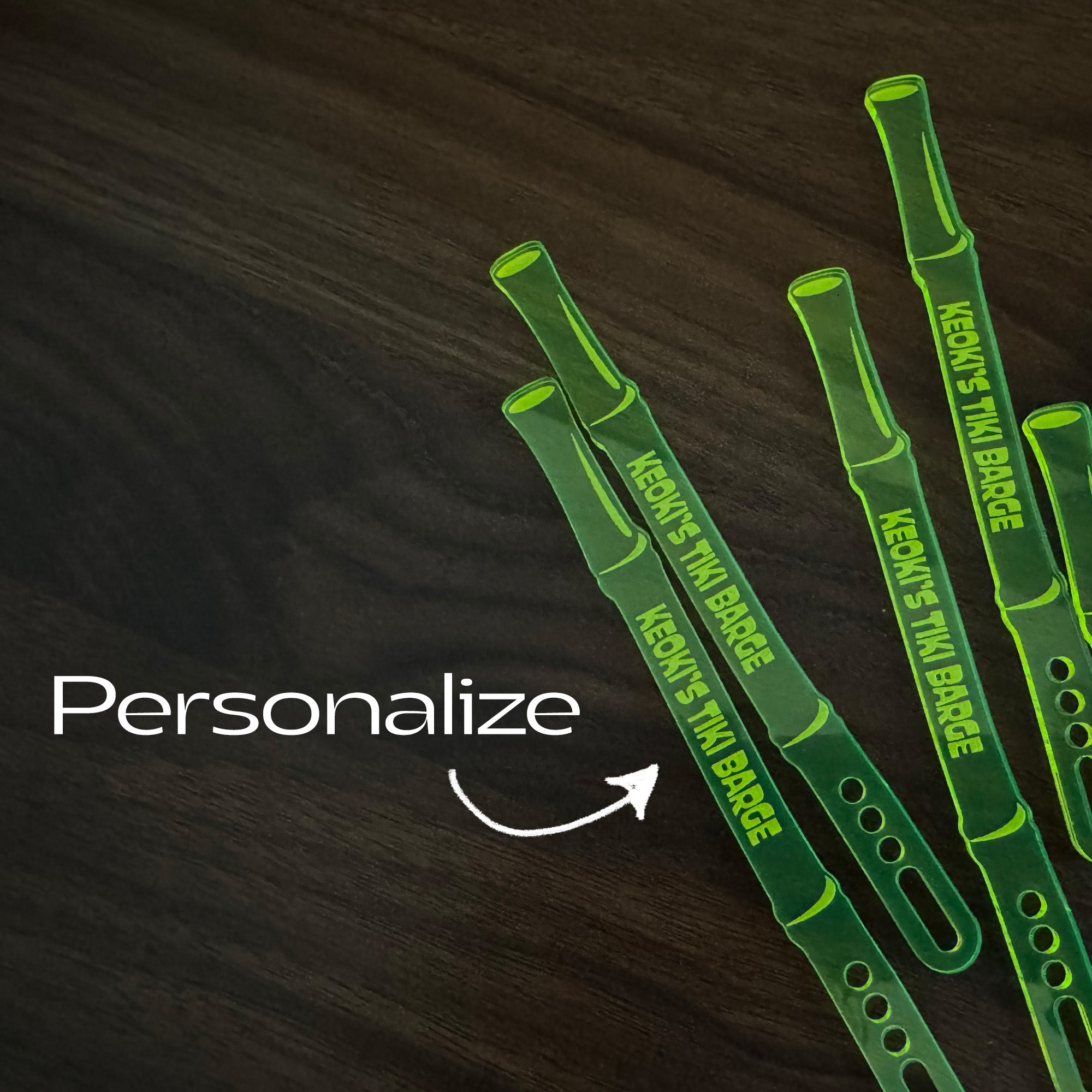 Bamboo Personalized Stubbie Cocktail Stirrers with 'Keoki's Tiki Barge' branding on a dark wooden surface, with text 'Personalize'.