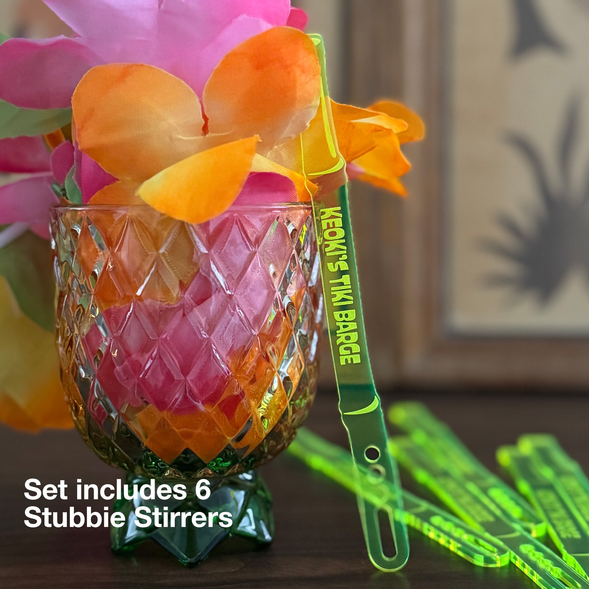 Set of Bamboo Personalized Stubbie Cocktail Stirrers with glass and flowers in the background