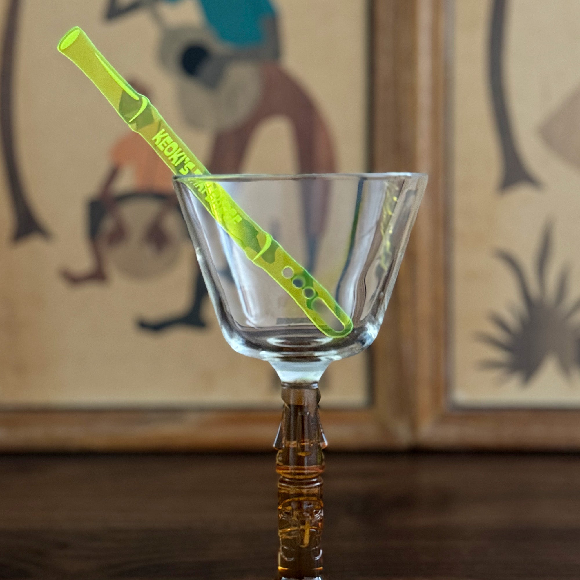 Clear glass with a Bamboo Personalized Stubbie Cocktail Stirrer against a blurred background
