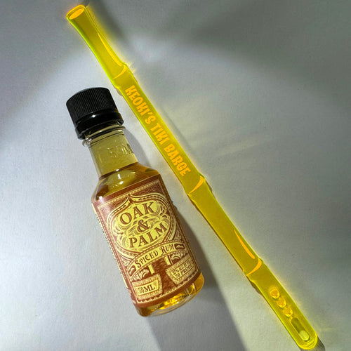 Small bottle of Oak & Palm Spiced Rum with a Bamboo Personalized XL Cocktail Stirrer on a light gray background