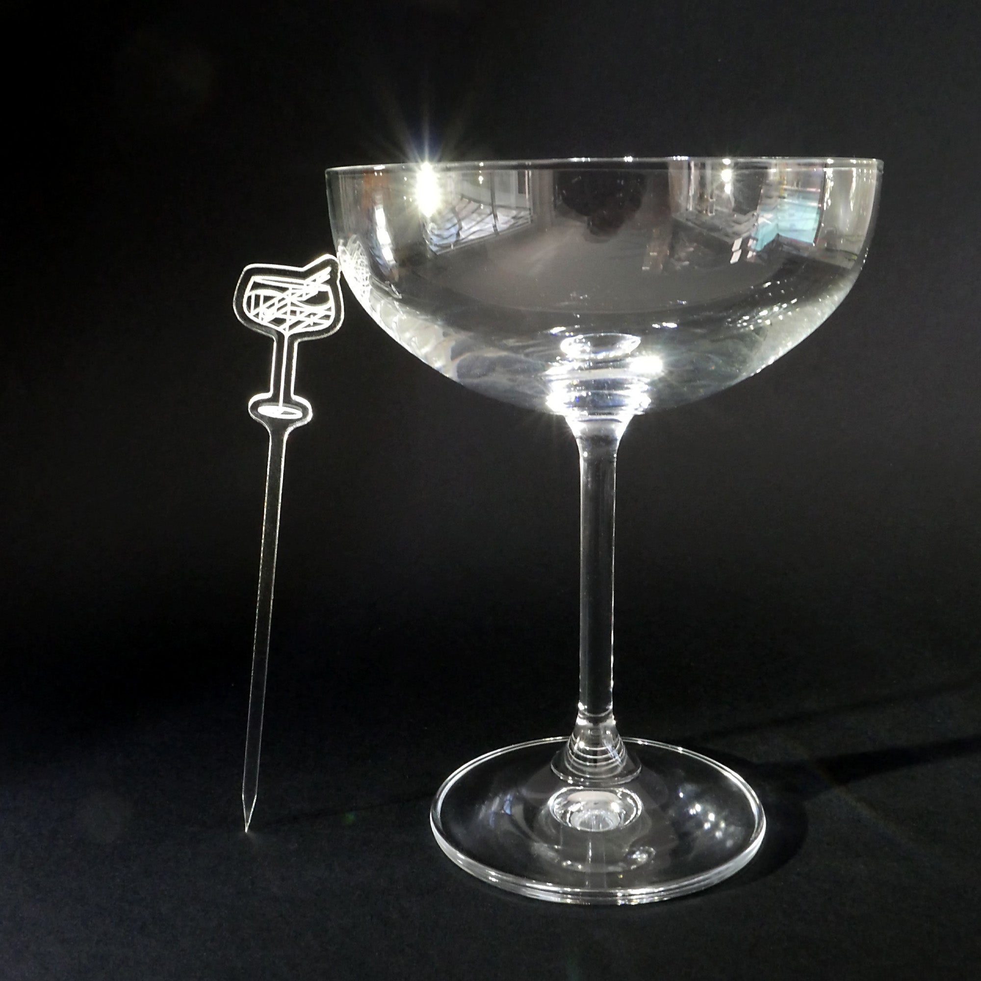 Clear cocktail glass with a Daiquiri Garnish Pick on a black background