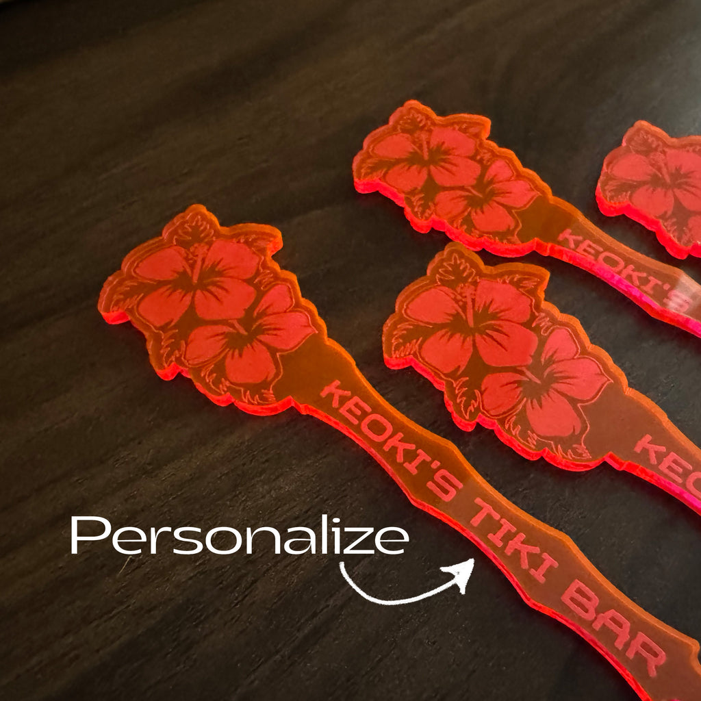 Hibiscus Flower Personalized Stubbie Drink Stirrer with floral design on a dark surface, featuring the brand 'KEOKI'.