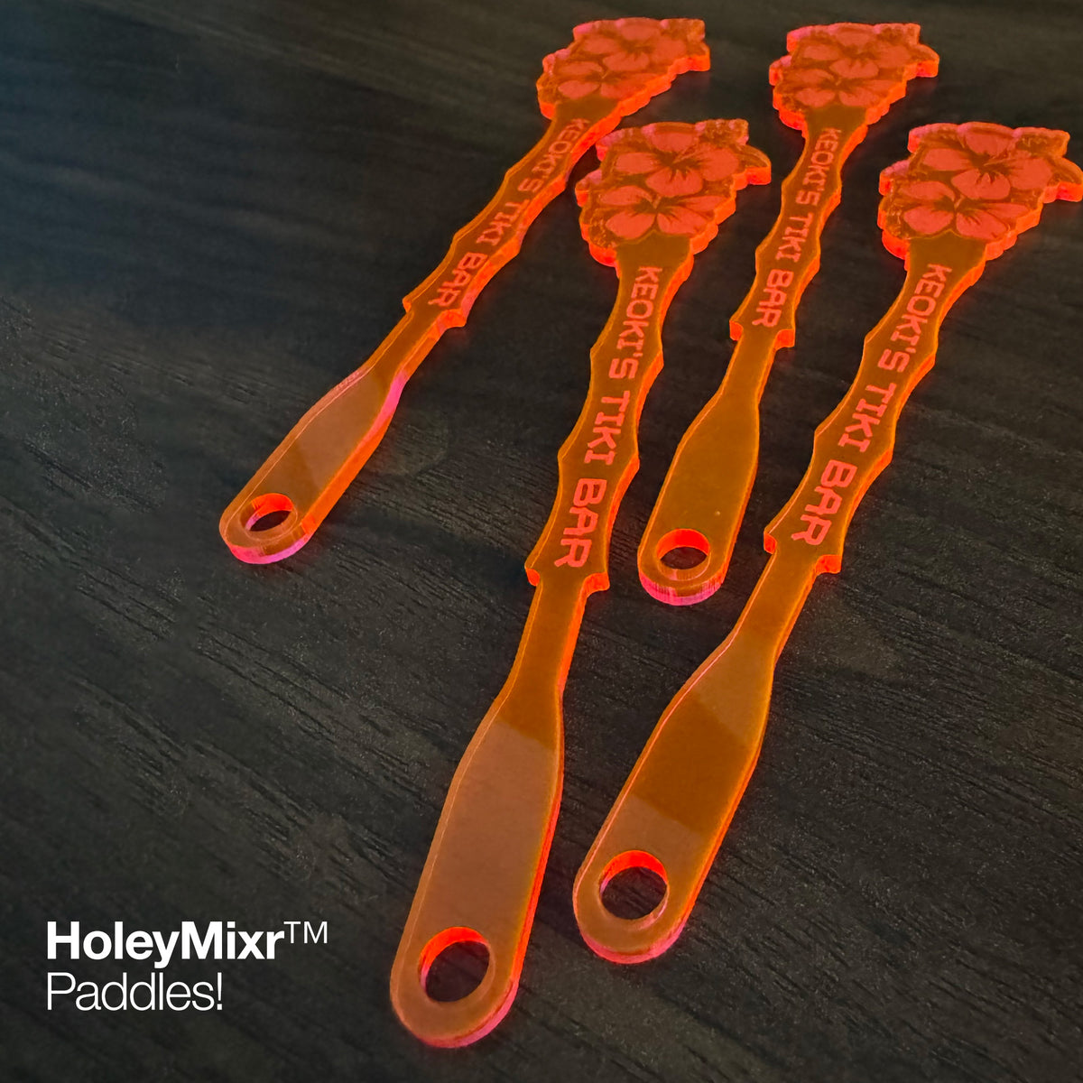 Hibiscus Flower Personalized Stubbie Drink Stirrers on a dark surface with brand name visible.