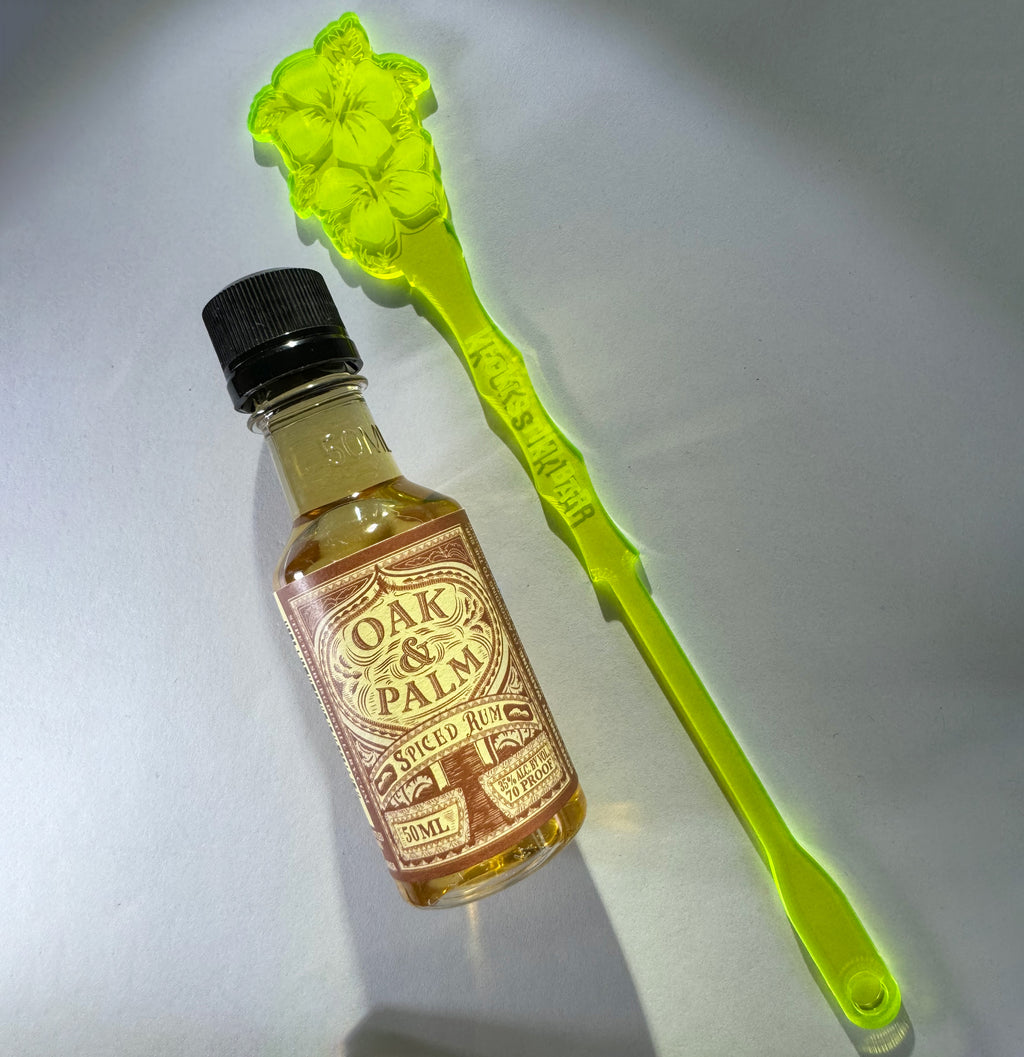 Small bottle of Oak & Palm Spiced Rum with a Hibiscus Flower Personalized XL Drink Stirrer on a light gray background