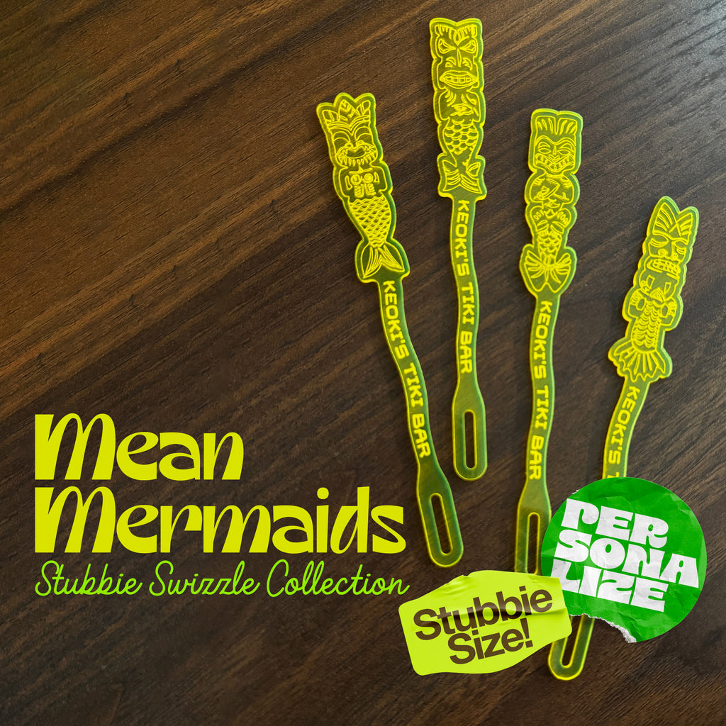 Mean Mermaids Personalized Stubbie Swizzle Sticks arranged on a dark wood surface, with large white text and two colorful promotional badges.