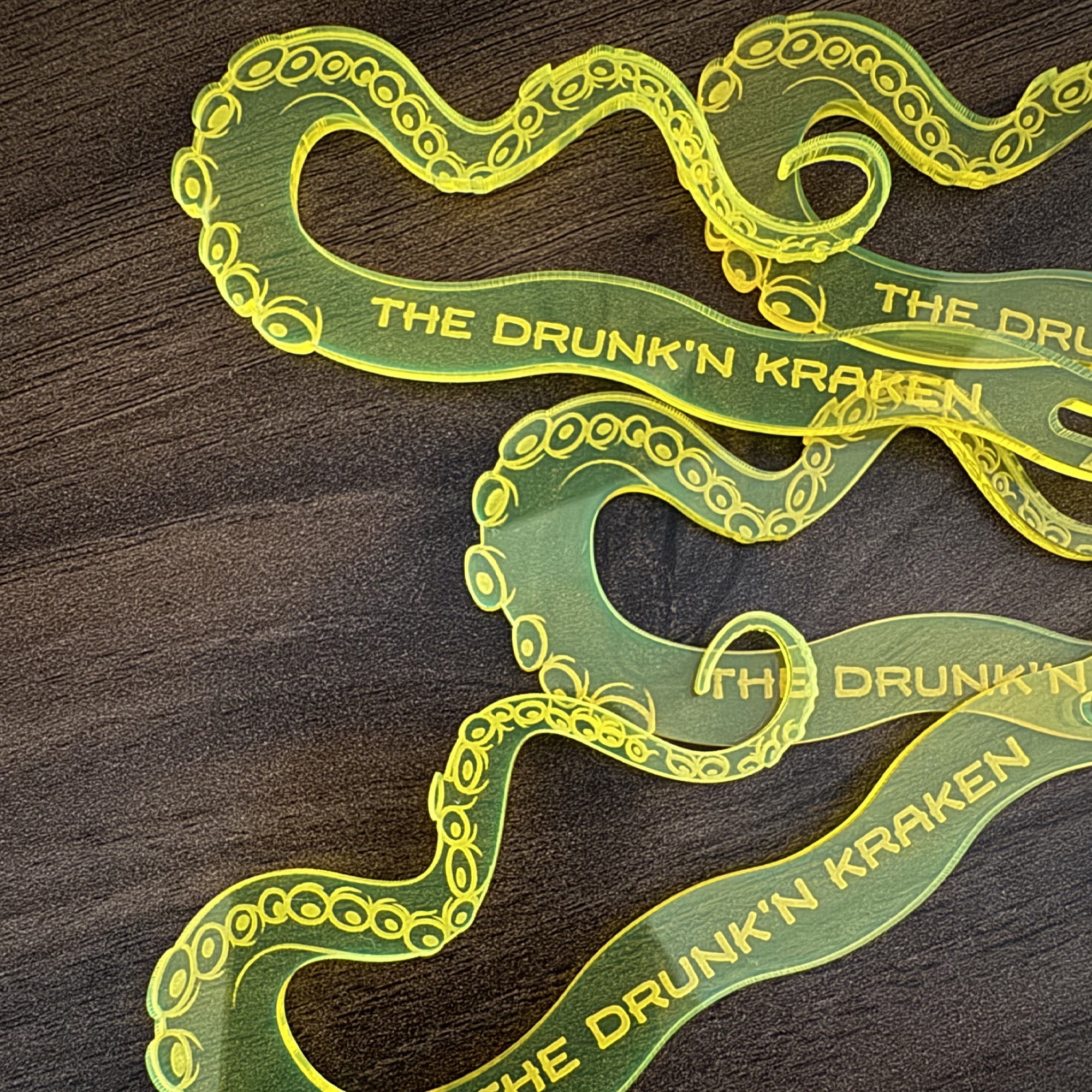 Octopus Tentacle "The Drunken Kraken" Personalized Stubbie Swizzle Sticks with 'The Drunk'n Kraken' text on a wooden surface.