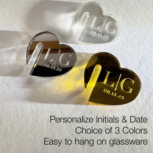 Heart-shaped drink charms for the edge of a glass with engraved initials and date on a white background