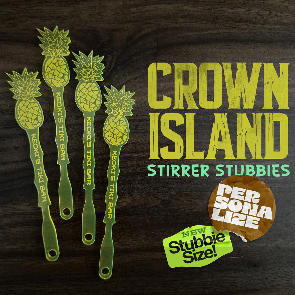 Pineapple drink stirrer stubbies with 'Crown Island' branding on a dark background