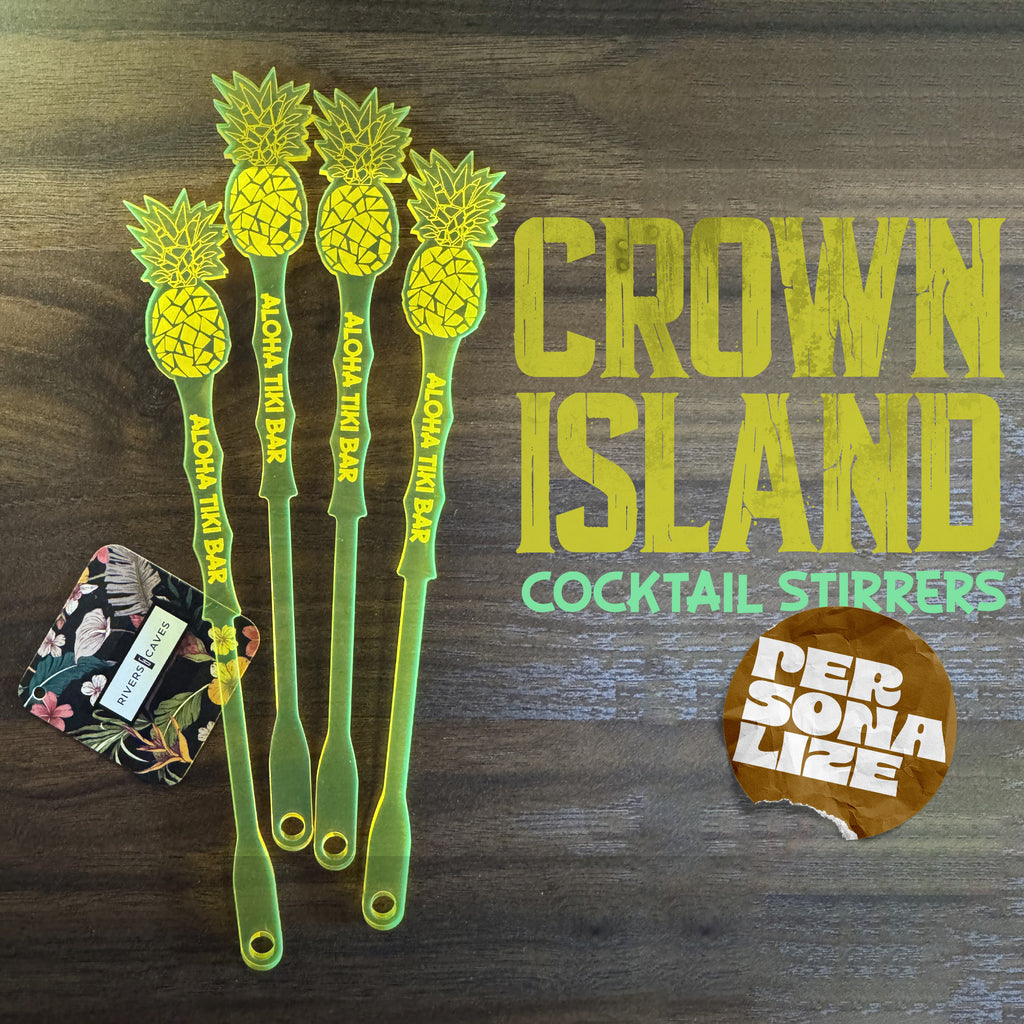 Set of Pineapple shaped personalized cocktail drink stirrers with 'Crown Island' branding on a wooden surface.