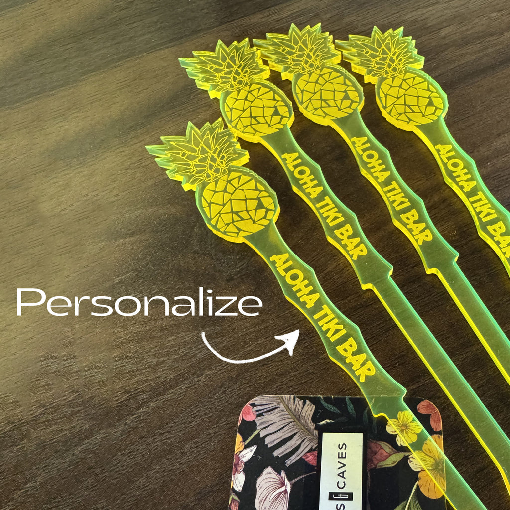 Pineapple Drink Stirrers with 'Aloha Tiki Bar' text on a wooden surface, featuring the word personalize and a floral design in the corner.