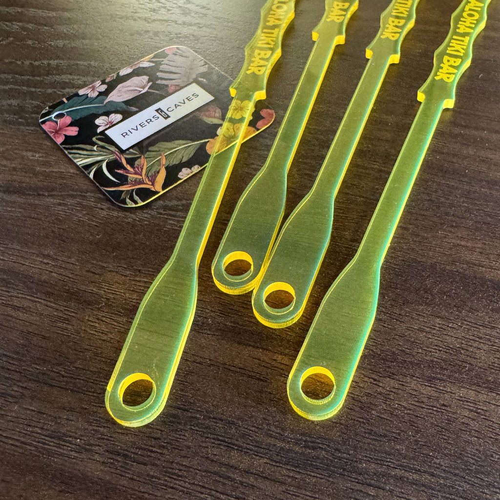 Personalized Pineapple Drink Stirrers  on a wooden surface with a card featuring floral designs and text.