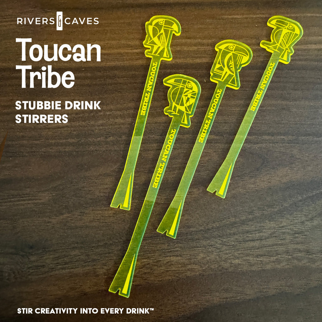 Four translucent neon yellow-green toucan logo shaped drink stirrers arranged on a dark wood background, with white text reading 'Rivers Caves Toucan Tribe Stubbie Drink Stirrers' and 'Stir Creativity Into Every Drink'.