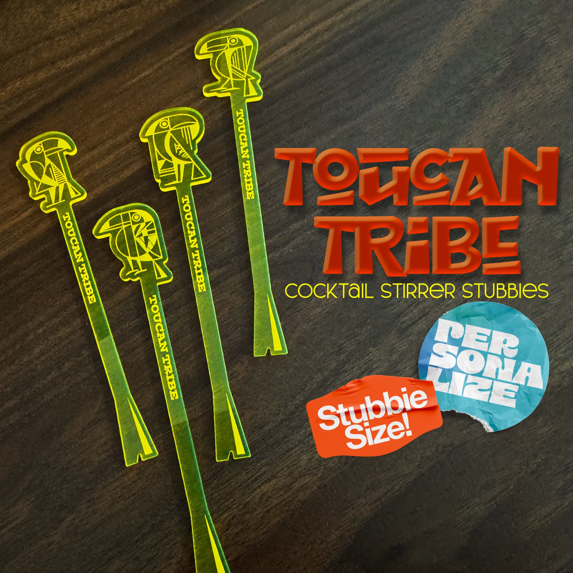Image Toucan Tribe Cocktail Stirrer Stubbies Cover. Four Stirrer designs on a wood tabletop with 2 badges reading 'Stubbie Size' and 'Personalize'